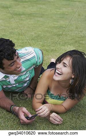 Close-up of a young couple lying in a lawn and smiling View Large Photo Image Stock Image - Close-up of a young couple lying in a lawn and smiling. Fotosearch