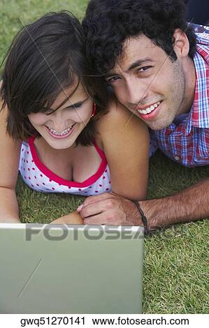 Close-up of a young couple lying in a lawn in front of a laptop View Large Photo Image Stock Image - Close-up of a young couple lying in a lawn in front of a laptop. Fotosearch