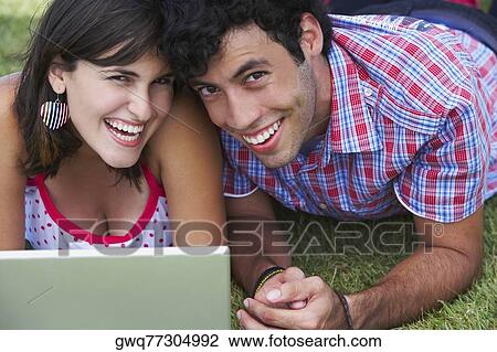 Close-up of a young couple lying in a lawn in front of a laptop View Large Photo Image Stock Image - Close-up of a young couple lying in a lawn in front of a laptop. Fotosearch