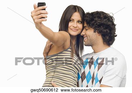 Close-up of a young couple taking a photograph of themselves with a mobile phone View Large Photo Image Stock Image - Close-up of a young couple taking a photograph of themselves with a mobile phone. Fotosearch