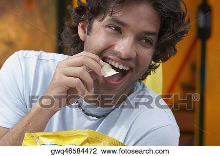 Close-up of a young man eating potato chips View Large Photo Image Stock Image - Close-up of a young man eating potato chips. Fotosearch