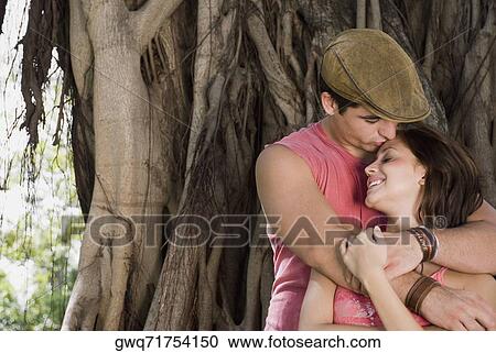 Close-up of a young man embracing a young woman from behind and smiling View Large Photo Image Stock Image - Close-up of a young man embracing a young woman from behind and smiling. Fotosearch