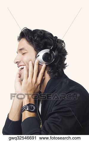 Close-up of a young man listening to music and smiling View Large Photo Image Stock Image - Close-up of a young man listening to music and smiling. Fotosearch