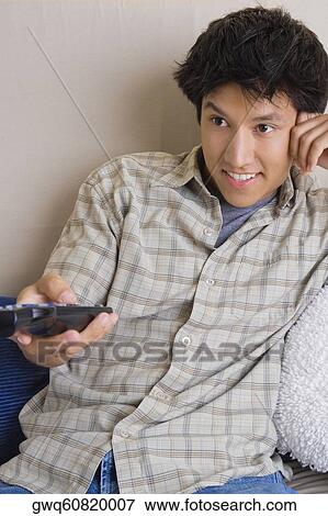 Close-up of a young man operating a remote control View Large Photo Image Stock Photo - Close-up of a young man operating a remote control. Fotosearch