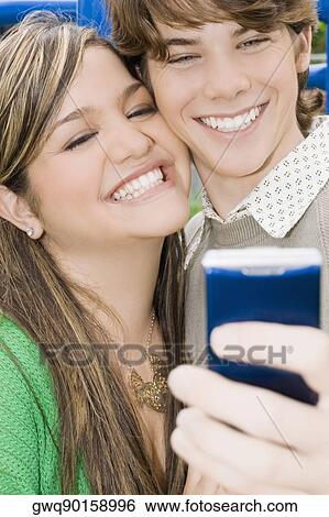 Close-up of a young woman and a teenage boy looking at a mobile phone and smiling View Large Photo Image Stock Photograph - Close-up of a young woman and a teenage boy looking at a mobile phone and smiling. Fotosearch