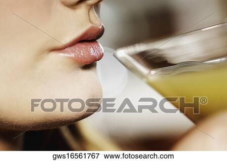 Stock Photo - Close-up of a young woman drinking a glass of cocktail. Fotosearch