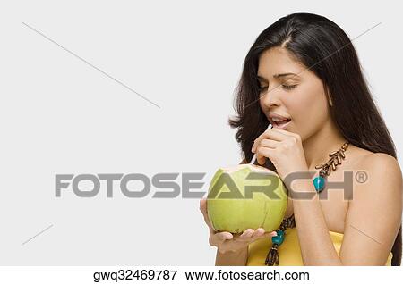 Stock Photo - Close-up of a young woman drinking coconut milk. Fotosearch