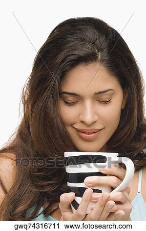 Close-up of a young woman holding a mug of coffee and smiling View Large Photo Image Stock Image - Close-up of a young woman holding a mug of coffee and smiling. Fotosearch