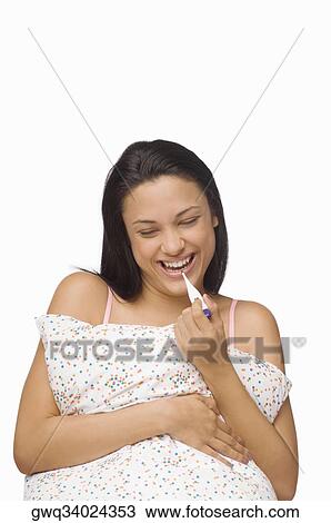 Stock Image - Close-up of a young woman holding a digital thermometer and smiling. Fotosearch