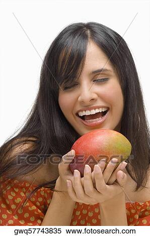 Stock Photography - Close-up of a young woman holding a mango and laughing. Fotosearch