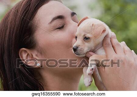 Close-up of a young woman kissing a puppy View Large Photo Image Stock Image - Close-up of a young woman kissing a puppy. Fotosearch