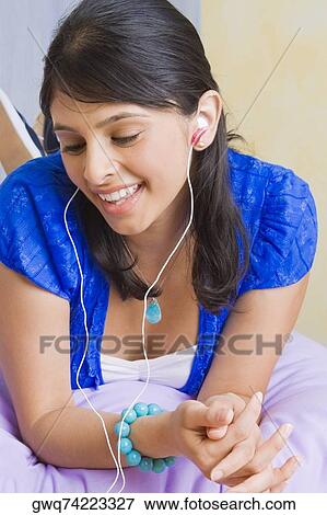 Stock Photo - Close-up of a young woman listening to music with earbuds. Fotosearch
