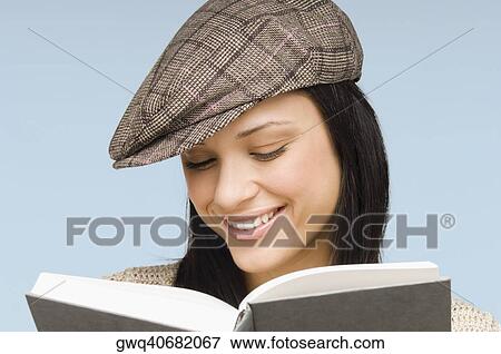 Stock Photo - Close-up of a young woman reading a book and smiling. Fotosearch