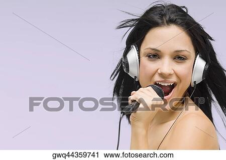 Close-up of a young woman singing into a microphone View Large Photo Image Stock Image - Close-up of a young woman singing into a microphone. Fotosearch