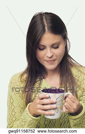 Close-up of a young woman standing and holding a cup of coffee View Large Photo Image Stock Image - Close-up of a young woman standing and holding a cup of coffee. Fotosearch