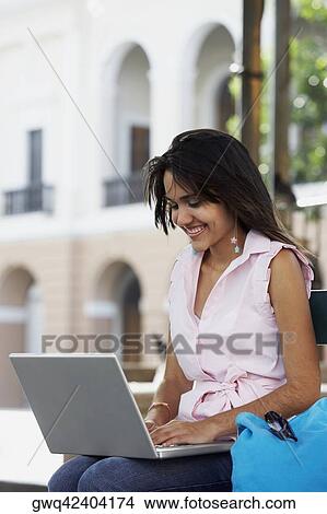 Close-up of a young woman using a laptop and smiling, Old San Juan, San Juan, Puerto Rico View Large Photo Image Picture - Close-up of a young woman using a laptop and smiling, Old San Juan, San Juan, Puerto Rico. Fotosearch