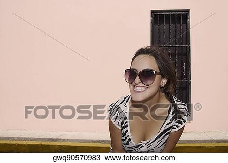 Close-up of a young woman wearing sunglasses and smiling View Large Photo Image Stock Image - Close-up of a young woman wearing sunglasses and smiling. Fotosearch