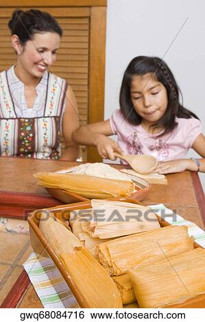 Stock Photograph - Girl preparing bread with her mother in the kitchen. Fotosearch
