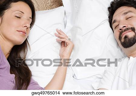 High angle view of a mid adult couple sleeping on the bed View Large Photo Image Picture - High angle view of a mid adult couple sleeping on the bed. Fotosearch