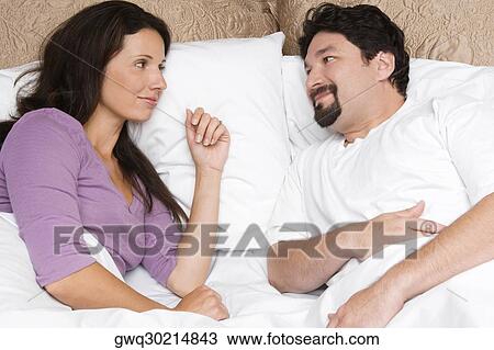 High angle view of a mid adult couple lying on the bed and looking at each other View Large Photo Image Stock Image - High angle view of a mid adult couple lying on the bed and looking at each other. Fotosearch