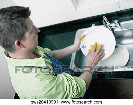 High angle view of a mid adult man washing plates at a kitchen sink View Large Photo Image Stock Image - High angle view of a mid adult man washing plates at a kitchen sink. Fotosearch