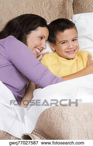 High angle view of a mid adult woman hugging her son on the bed View Large Photo Image Stock Photo - High angle view of a mid adult woman hugging her son on the bed. Fotosearch