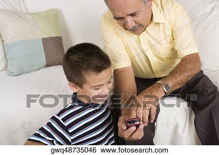 High angle view of a senior man showing a mobile phone to his grandson View Large Photo Image Stock Photograph - High angle view of a senior man showing a mobile phone to his grandson. Fotosearch