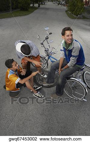High angle view of a teenage boy and a boy gesturing at their friend sitting on a low rider bicycle View Large Photo Image Stock Image - High angle view of a teenage boy and a boy gesturing at their friend sitting on a low rider bicycle. Fotosearch