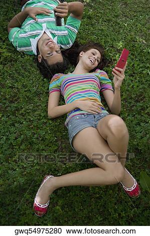 High angle view of a young couple lying in a park and using mobile phones View Large Photo Image Stock Image - High angle view of a young couple lying in a park and using mobile phones. Fotosearch