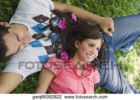 Stock Image - High angle view of a young couple lying in a park. Fotosearch