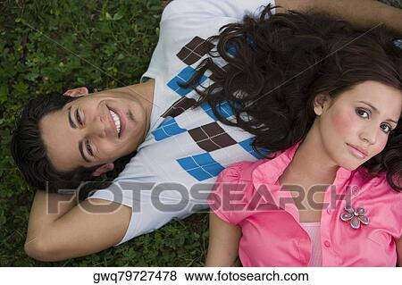 Stock Photo - High angle view of a young couple lying in a park. Fotosearch