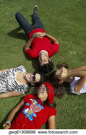 High angle view of a young man lying on grass with three young women View Large Photo Image Stock Photo - High angle view of a young man lying on grass with three young women. Fotosearch