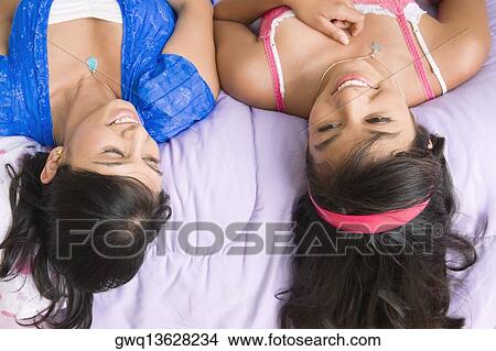 High angle view of a young woman and a teenage girl lying on the bed and smiling View Large Photo Image Picture - High angle view of a young woman and a teenage girl lying on the bed and smiling. Fotosearch