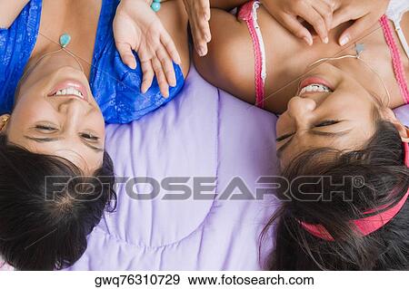 High angle view of a young woman and a teenage girl lying on the bed and smiling View Large Photo Image Stock Photo - High angle view of a young woman and a teenage girl lying on the bed and smiling. Fotosearch