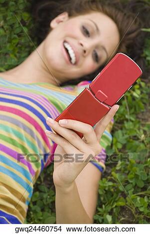 High angle view of a young woman holding a mobile phone and smiling View Large Photo Image Picture - High angle view of a young woman holding a mobile phone and smiling. Fotosearch