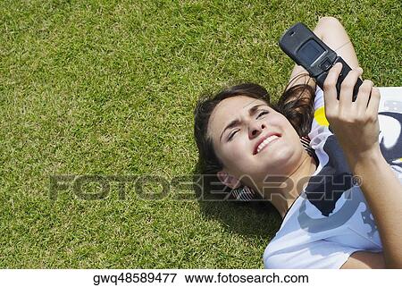 High angle view of a young woman text messaging and smiling View Large Photo Image Stock Photo - High angle view of a young woman text messaging and smiling. Fotosearch