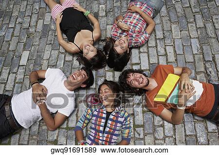 Stock Photo - High angle view of three young women with two young men lying on cobblestone and smiling, Old San Juan, San Juan, Puerto Rico. Fotosearch