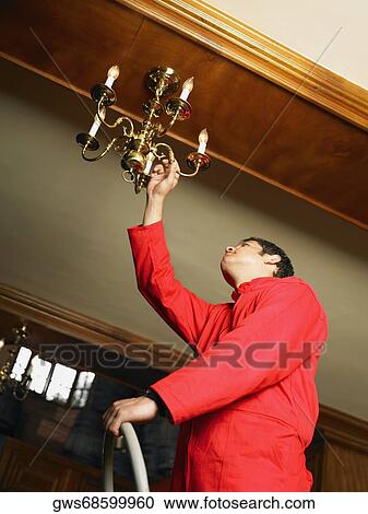 Low angle view of a waiter adjusting a chandelier View Large Photo Image Stock Image - Low angle view of a waiter adjusting a chandelier. Fotosearch