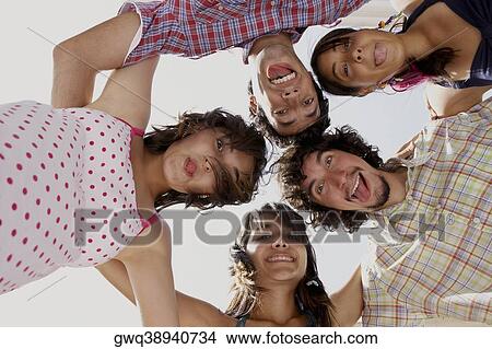 Picture - Low angle view of three young women and two young men in a huddle. Fotosearch