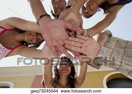 Low angle view of three young women and two young men in a huddle View Large Photo Image Picture - Low angle view of three young women and two young men in a huddle. Fotosearch