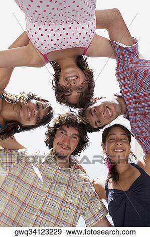 Low angle view of three young women and two young men in a huddle View Large Photo Image Stock Photo - Low angle view of three young women and two young men in a huddle. Fotosearch