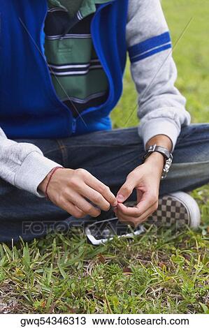 Low section view of a teenage boy sitting in a park View Large Photo Image Stock Image - Low section view of a teenage boy sitting in a park. Fotosearch