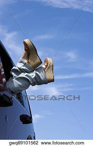 Stock Image - Low section view of a woman in a car with her legs outside the window. Fotosearch