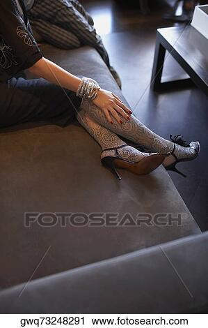 Low section view of a woman sitting on a couch View Large Photo Image Stock Image - Low section view of a woman sitting on a couch. Fotosearch
