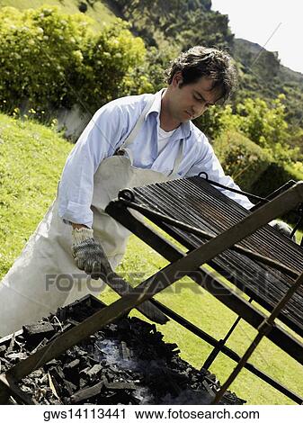 Mid adult man preparing a barbecue grill View Large Photo Image Stock Image - Mid adult man preparing a barbecue grill. Fotosearch
