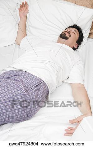 Mid adult man sleeping on the bed View Large Photo Image Picture - Mid adult man sleeping on the bed. Fotosearch