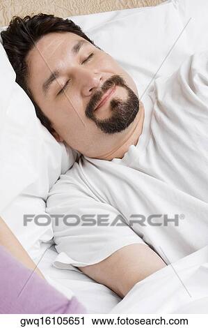 Mid adult man sleeping on the bed View Large Photo Image Stock Image - Mid adult man sleeping on the bed. Fotosearch