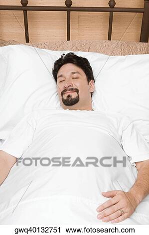 Mid adult man sleeping on the bed View Large Photo Image Stock Image - Mid adult man sleeping on the bed. Fotosearch
