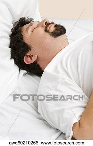 Stock Photograph - Mid adult man sleeping on the bed. Fotosearch