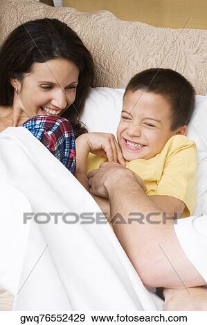 Mid adult man tickling his son with a mid adult woman lying beside them View Large Photo Image Stock Photo - Mid adult man tickling his son with a mid adult woman lying beside them. Fotosearch